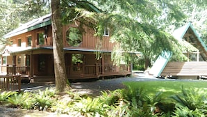 A wooden cabin with a porch, a deck, and a small slide.