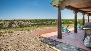 A covered outdoor area with a barbecue grill, seating, and a view of a hilly landscape. - Chisholm Cabin on the North Rim (Canyon)