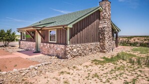 A rustic cabin with a stone chimney, wooden walls, and a green roof. - Chisholm Cabin on the North Rim (Canyon)