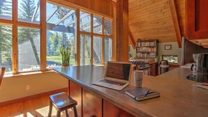 Una cocina con un ventanal grande, una laptop y una taza de café sobre el mostrador.