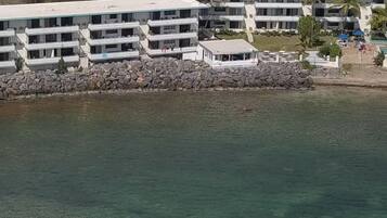 A coastal hotel with multiple buildings, a pool, and a rocky shoreline.