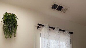 Une pièce avec une porte blanche, une plante suspendue et une main courante en bois.