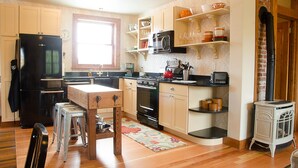 Una cocina compacta con armarios de madera, un refrigerador negro, una estufa y un microondas.