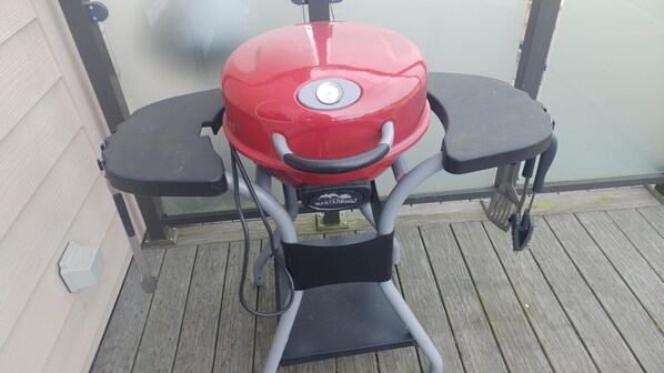 A red barbecue grill with a control panel and two black seats. - From The Mountaintops To The Sea (Port Angeles)