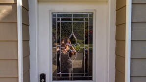 Une porte blanche avec le numéro « 129 » au-dessus, un panneau de verre orné d’un motif décoratif et un paillasson sur lequel est écrit le mot « BIENVENUE ».