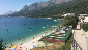 A coastal beach with clear blue waters, a sandy shore, and a mountainous backdrop. - Cozy House: first-row beach, ramp accessibility, hottub, AC, gasgrill, W/D prkng (Gradac)