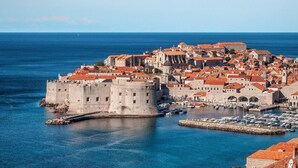 A coastal cityscape with a prominent historic fortress and a marina filled with boats. - Cozy House: first-row beach, ramp accessibility, hottub, AC, gasgrill, W/D prkng (Gradac)