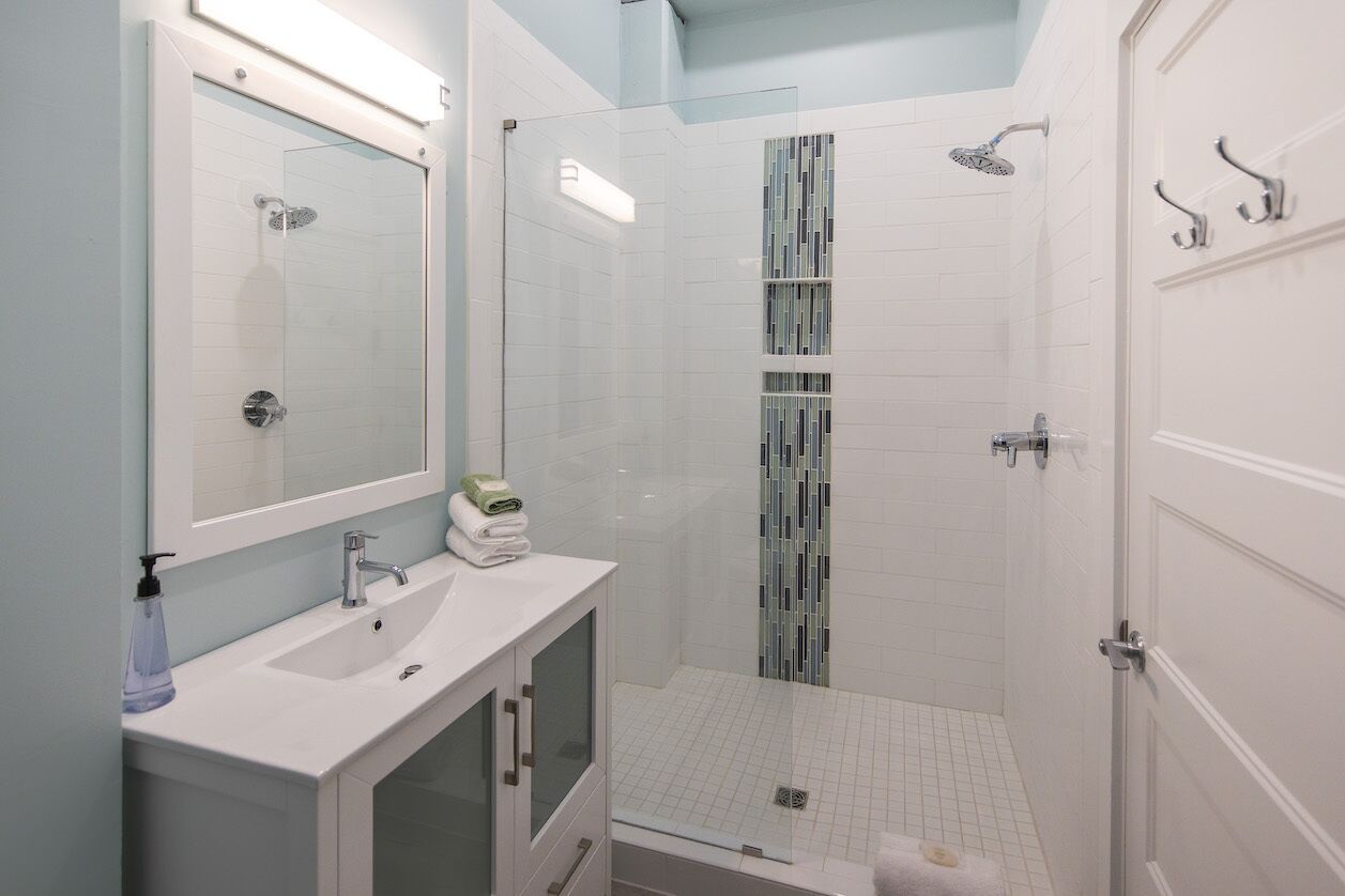 A modern bathroom with a glass-enclosed shower, a white sink, and a mirror above it.