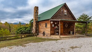 Ein rustikales Blockhaus mit einem Steinofen, einer Veranda und einem Schotterweg.