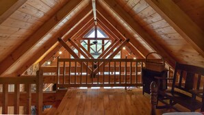 Ein Dachzimmer mit Holzbalken, einem Oberlicht und einem Hollgitter.