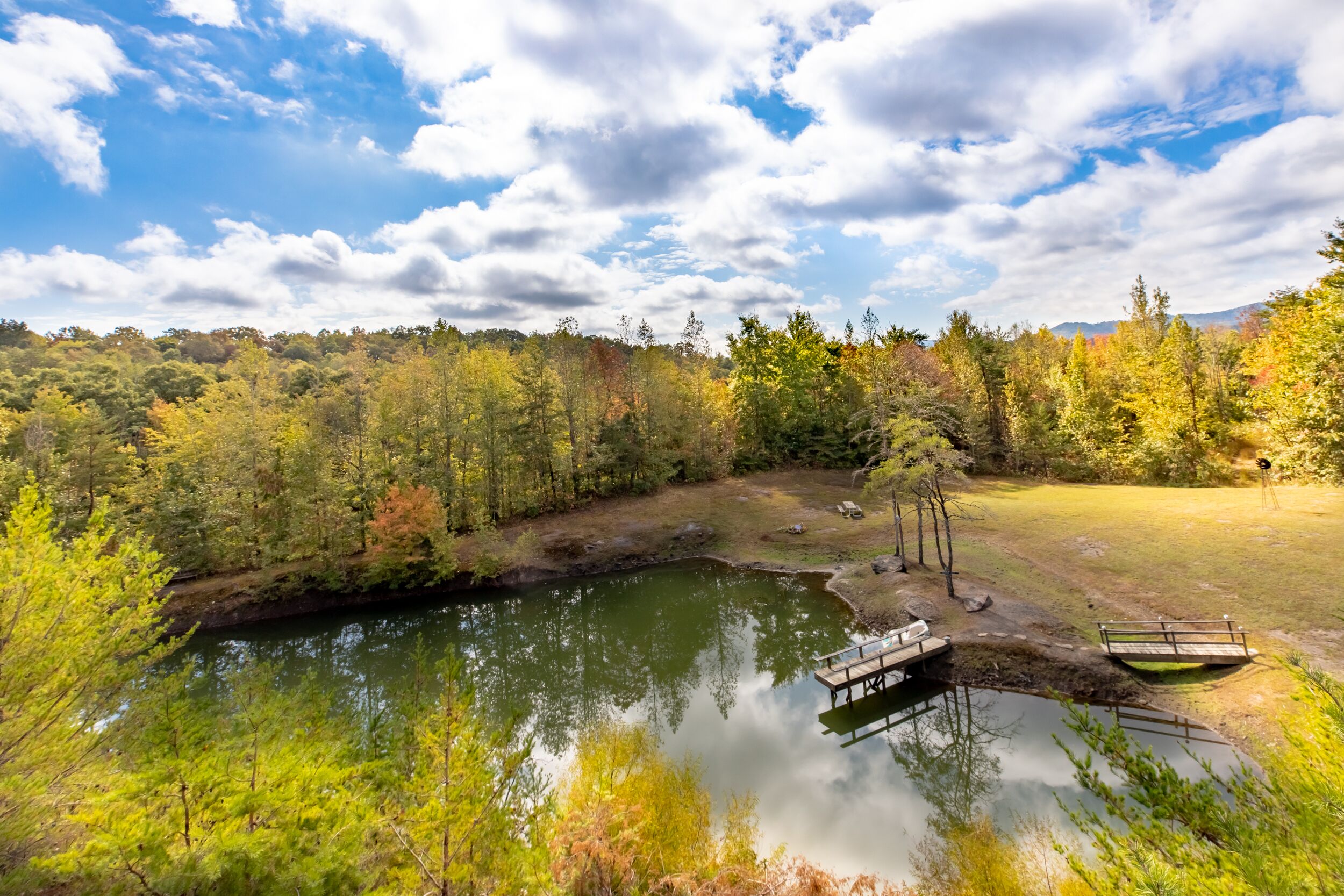 A serene lakeside setting with a dock, surrounded by autumn foliage and a clear sky.