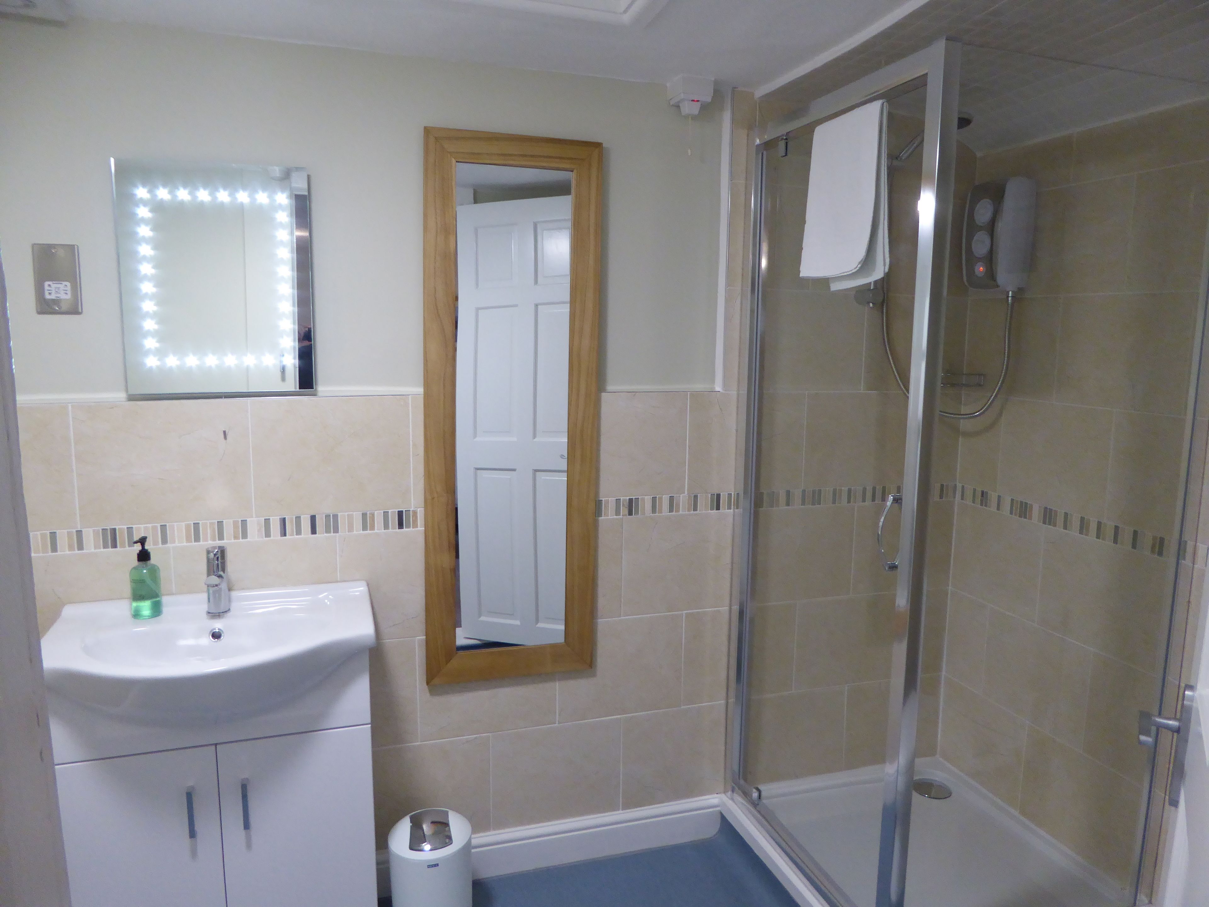 Un baño con lavamanos, espejo y ducha.