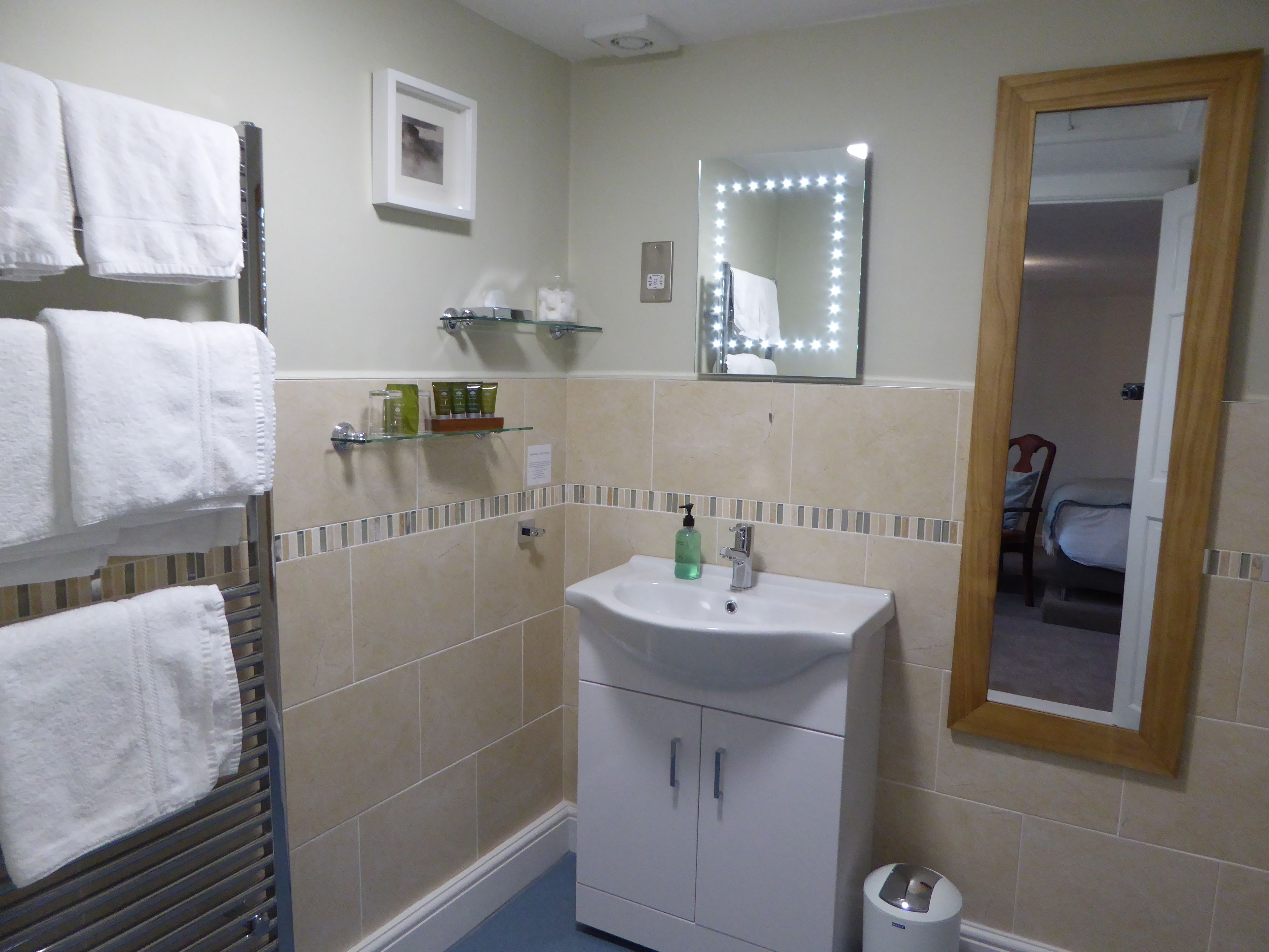 A bathroom with a sink, mirror, towel rack, and toiletries.
