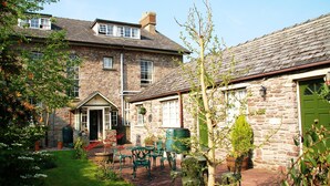 A stone building with a garden patio, outdoor seating, and a green door.
