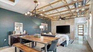 Una sala de estar moderna con una mesa de comedor de madera, un sofá y un televisor de pantalla plana.