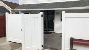 A white building with a grey roof, a white fence, and a wooden bench. - BEST BRIGANTINE VALUE! WE PAY BEACH FEES. WALK TO BEACH, EATERIES. 11AM CHECKOUT (Brigantine)
