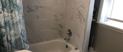 Un baño con bañera, lavamanos y ventana.