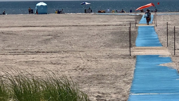 A beach with a blue pathway leading to the water, umbrellas, and beachgoers. - BEST BRIGANTINE VALUE! WE PAY BEACH FEES. WALK TO BEACH, EATERIES. 11AM CHECKOUT (Brigantine)