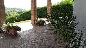 A covered patio area with a herringbone tile floor, brick pillars, and potted plants. - Villa Sofia Piedmont  (Montaldo Scarampi)