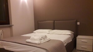 A neatly made bed with white linens and a rolled towel on the side. - Villa Sofia Piedmont  (Montaldo Scarampi)