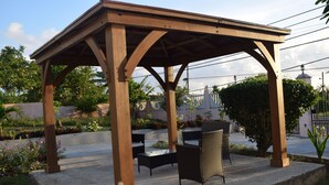 Une pergola en bois avec une table et des chaises, située dans un jardin.