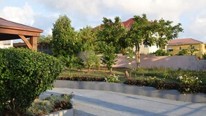 Un espace aménagé avec un chemin en béton, des haies taillées et une variété de plantes.