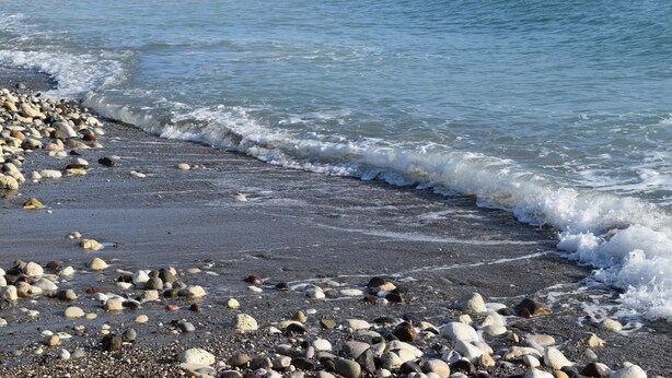 Une plage de galets, avec des vagues.