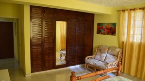 Une chambre à coucher avec un lit, une armoire en bois, un canapé et un tableau accroché au mur.