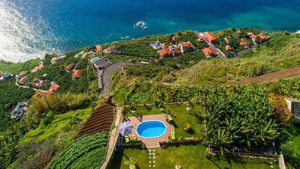 A coastal residential area with houses, a swimming pool, and a road. - SUN AND SUN HOUSE (Arco da Calheta)