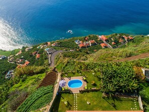 A coastal residential area with houses, a swimming pool, and a road. - SUN AND SUN HOUSE (Arco da Calheta)