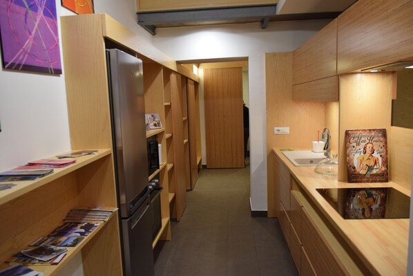 A narrow kitchen with wooden cabinets, a refrigerator, and a coffee machine. - All'Incanto di Mary Holiday House In The Historic Center Of Naples (Napoli)