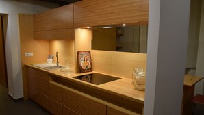Uma cozinha moderna com armários de madeira, bancada preta, pia e um espelho grande.