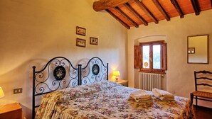 Une chambre à coucher avec un lit, une fenêtre, un radiateur, une chaise et une lampe.