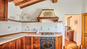 Une cuisine avec des meubles en bois, une cuisinière à gaz et un dosseret carrelé.