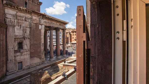 A view from a balcony overlooking ancient Roman architecture, including columns and a busy street below. - Stunning Pantheon View experience in the heart of Rome (Roma)