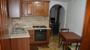 A compact kitchen with wooden cabinets, a gas stove, an oven, and a sink.