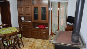A dining area with a wooden cabinet, a table with a green tablecloth, and a red bowl on the cabinet.