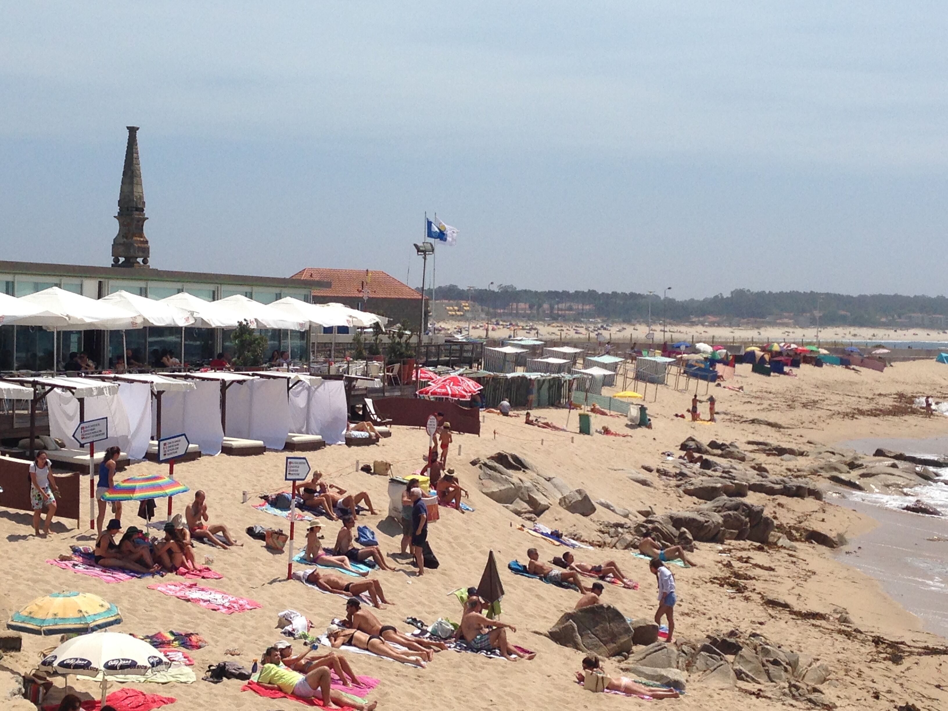 Une plage avec des parasols, des chaises longues et des gens qui se détendent.