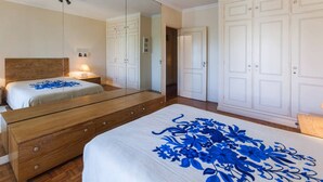 Une chambre à coucher avec un grand miroir, un lit en bois, une armoire blanche et une couvre-lit à motifs floraux.