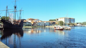 Un port où un grand voilier est amarré sur la gauche et où se trouvent des bateaux plus petits sur la droite.
