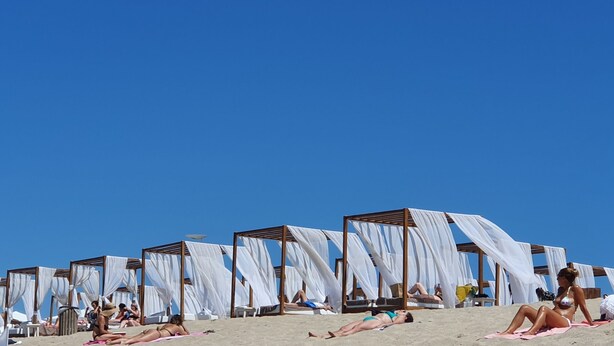 Une plage bordée de rangées de parasols blancs et de chaises longues.