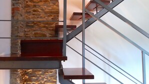 Un escalier moderne, avec un mur en pierre d’un côté et des rampes en métal.