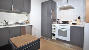 A modern kitchen with grey cabinets, a stainless steel range hood, and a built-in oven. - Dalí, charming and modern ground floor loft (Roma)