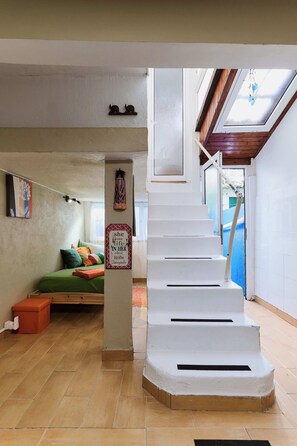 A staircase leading to a loft bedroom with a skylight, a small sofa, and a decorative sign.