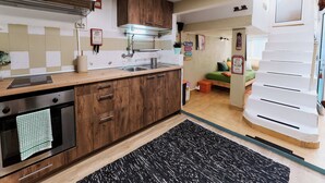 Eine Küche mit Holzausstattung, einem Edelstahlbackofen und einer gefliesten Spritzschutzwand.