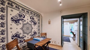 Ein Essbereich mit Tisch für zwei Personen, einer Wand mit Muster und Blick in die Küche.