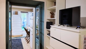 Ein Zimmer mit Fernseher auf einem weißen Schrank, einer Treppe, die in ein anderes Zimmer führt, und einer Tür zum Ausgang.