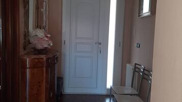 Ein Flur mit einer weißen Tür, einem Holzschrank mit Spiegel und einem Stuhl.