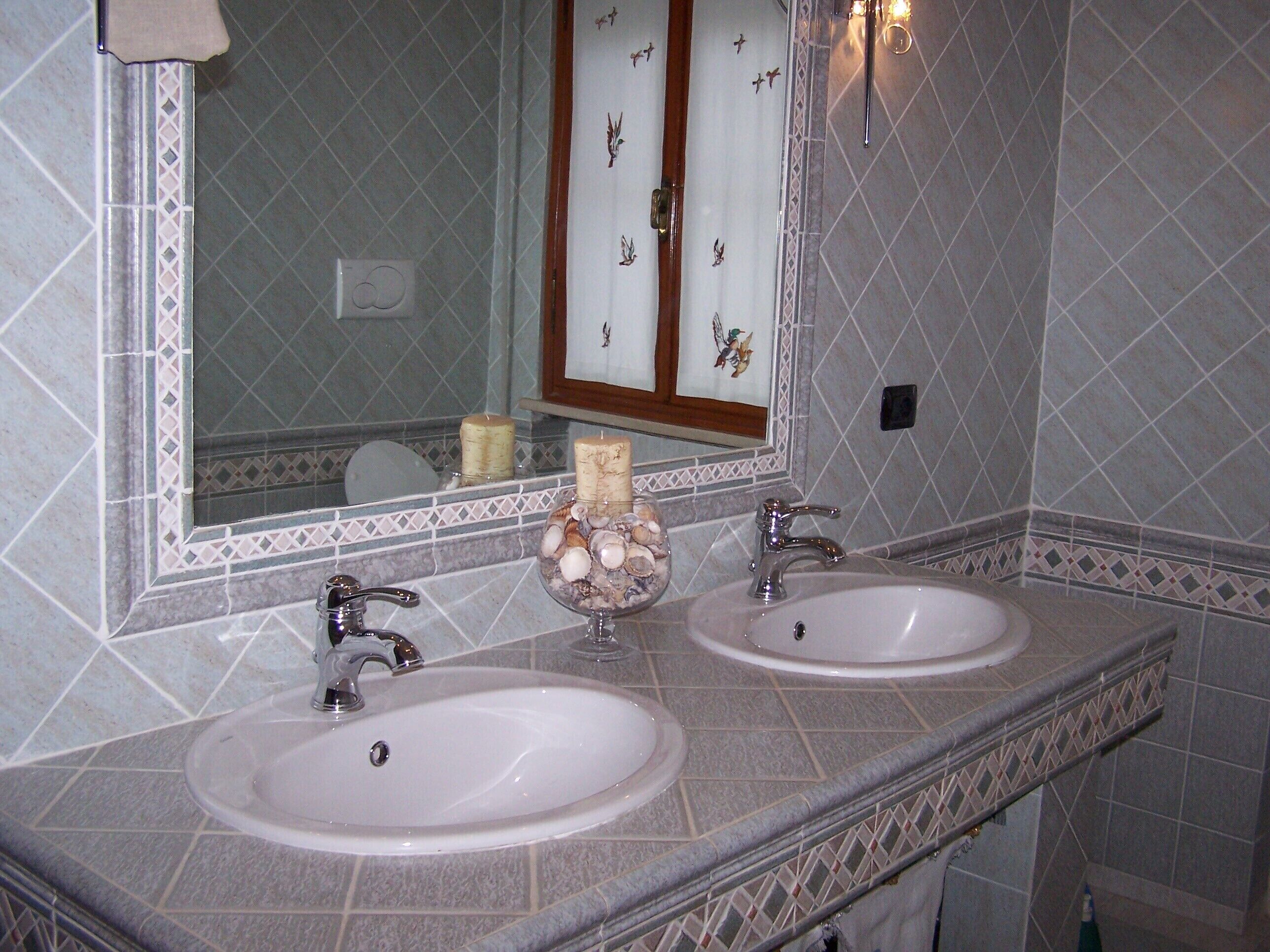 Une salle de bain avec deux lavabos, un miroir et des carreaux décoratifs.