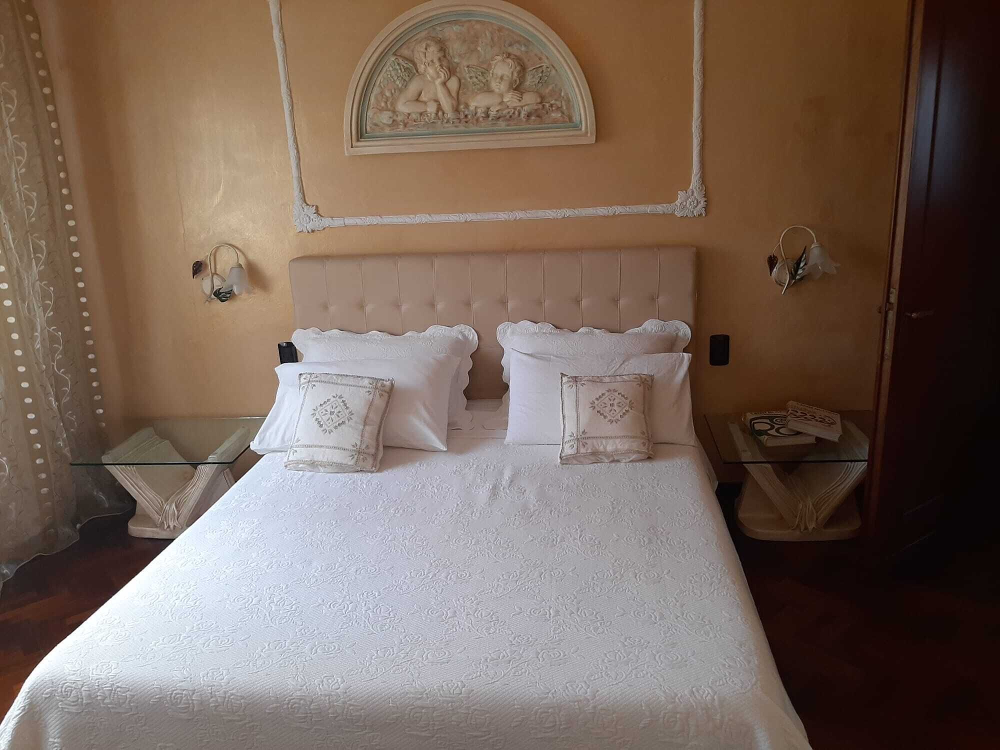 A neatly made bed with a tufted headboard, two bedside tables, and a decorative wall piece above the bed.